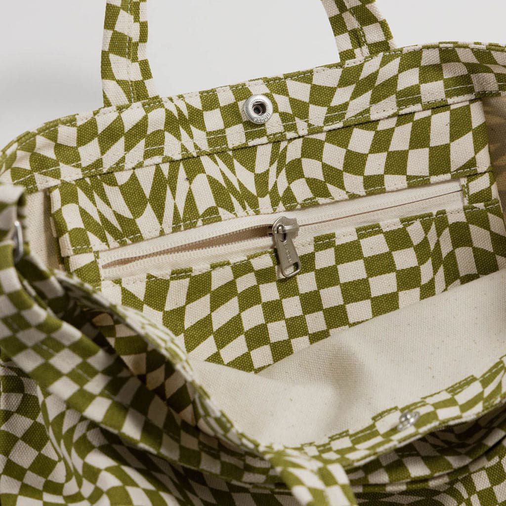 Close up of the interior of the bag. Side zipper is shown slightly unzipped. A metal clasp is positioned below the stitched handles. 