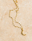 A gold chain necklace with a crescent moon pendant.