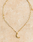 A gold chain necklace with a crescent moon pendant.