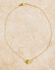 A thin gold necklace with a half sunburst pendant in the center.