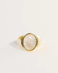 A statement gold signet ring with an oval mother of pearl stone set in the center.