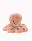A pink octopus stuffed animal with a smiling face, photographed on a cream background.