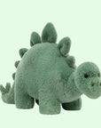On a white background is a green stegosaurus stuffed animal.