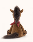 Soft stuffed animal in the shape of a brown horse with fluffy dark brown mane and tail, and wearing a red and white spotted bandana around its neck.
