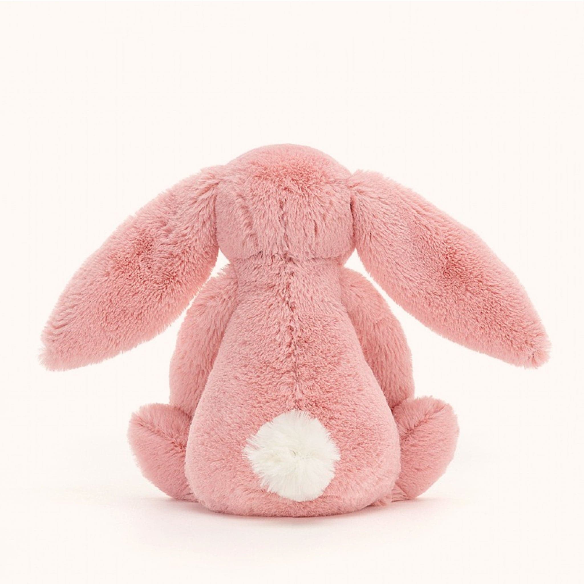 The back view of the fuzzy pink bunny stuffed animal with a white fuzzy ball as a tail and long floppy ears.