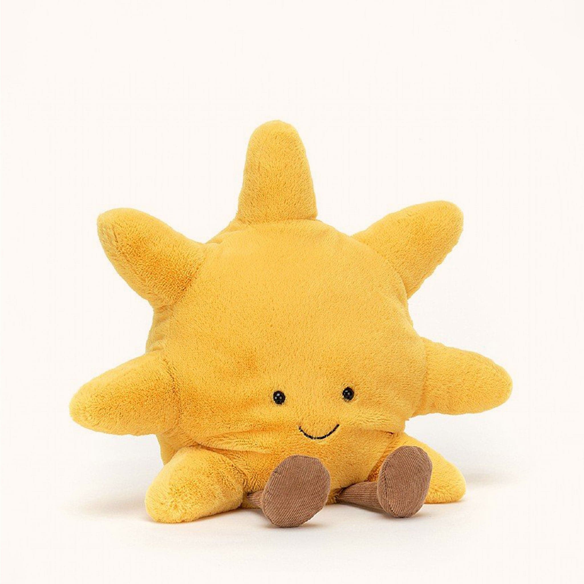 Soft stuffed animal in the shape of a yellow sun, with a smiley face and floppy brown legs.