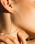 A model wearing these hoop earrings that are super thin and gold.