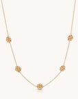 Gold chain necklace with five spaced out beaded flower details.