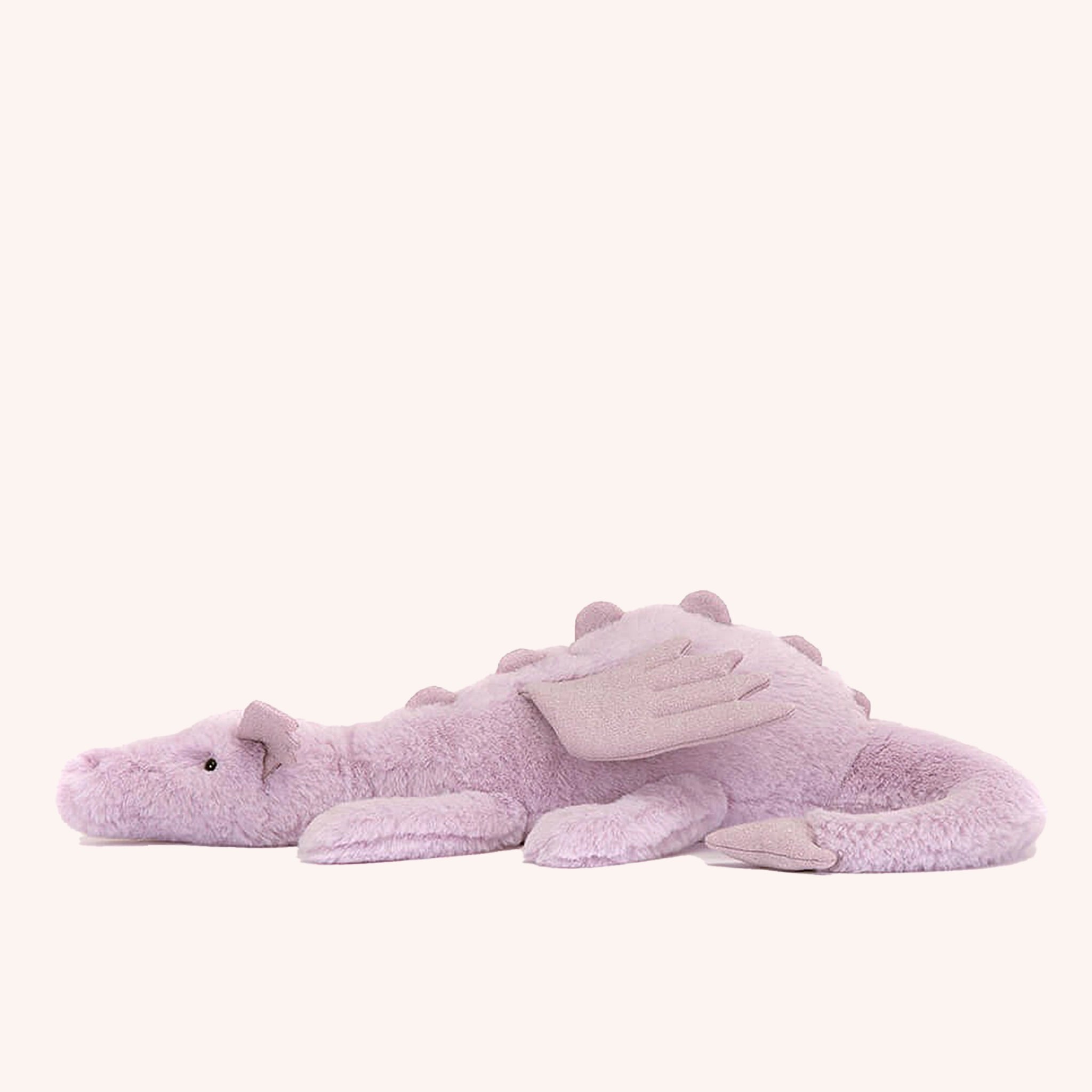 On a white background is a light purple dragon stuffed animal with wings, a sweet face and a long tail.