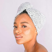 A white microfiber hair towel with tiny black polka dot design all over being modeled wrapping up wet hair.