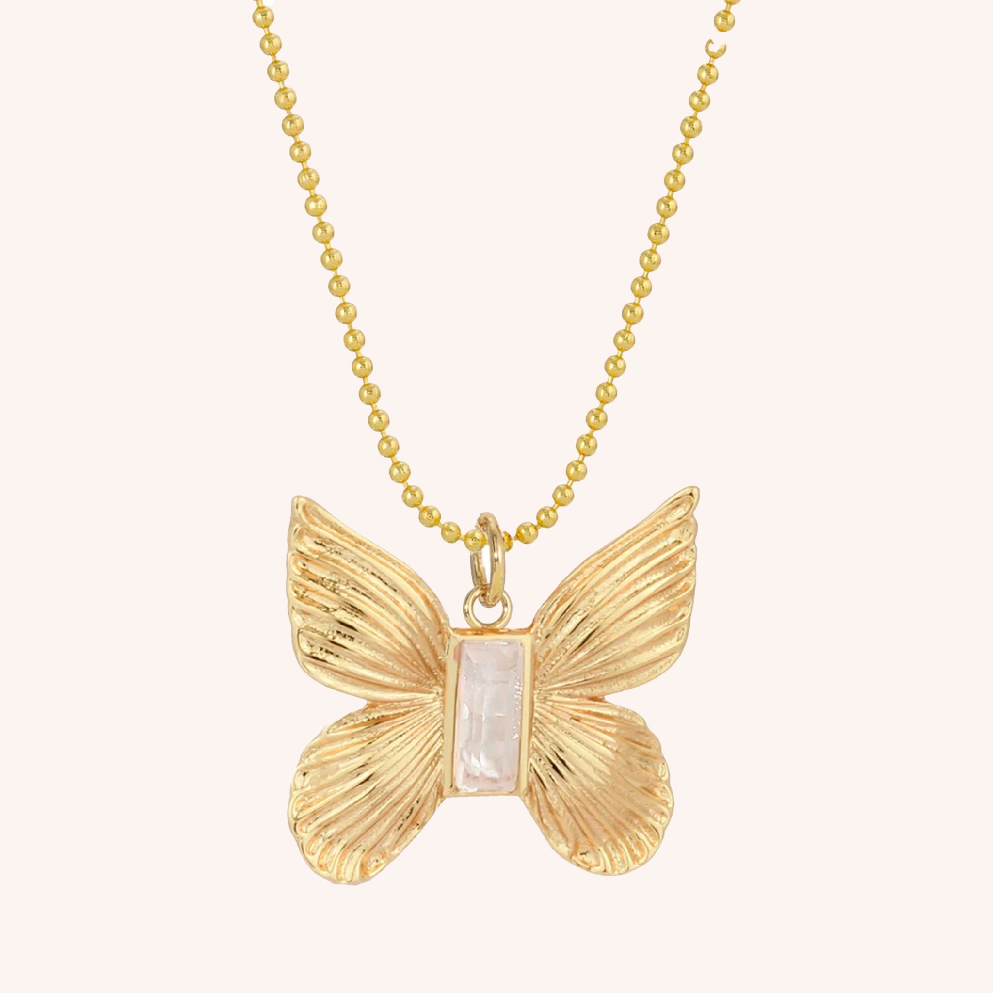A gold ball chain necklace with a gold butterfly pendant with a baguette mother of pearl stone in the center.
