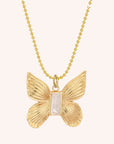 A gold ball chain necklace with a gold butterfly pendant with a baguette mother of pearl stone in the center.