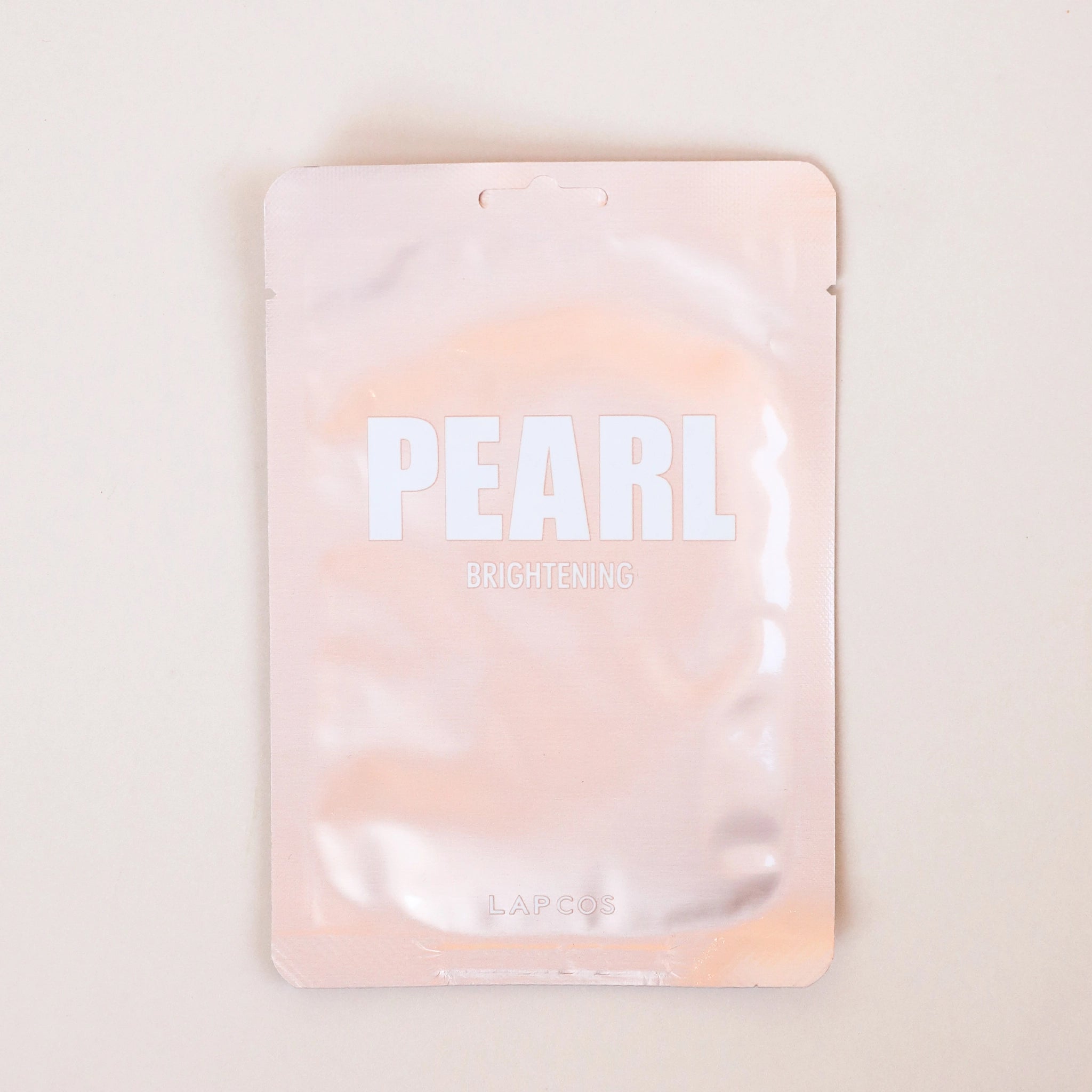 A rose gold pouch containing a face mask reads pearl brightening.