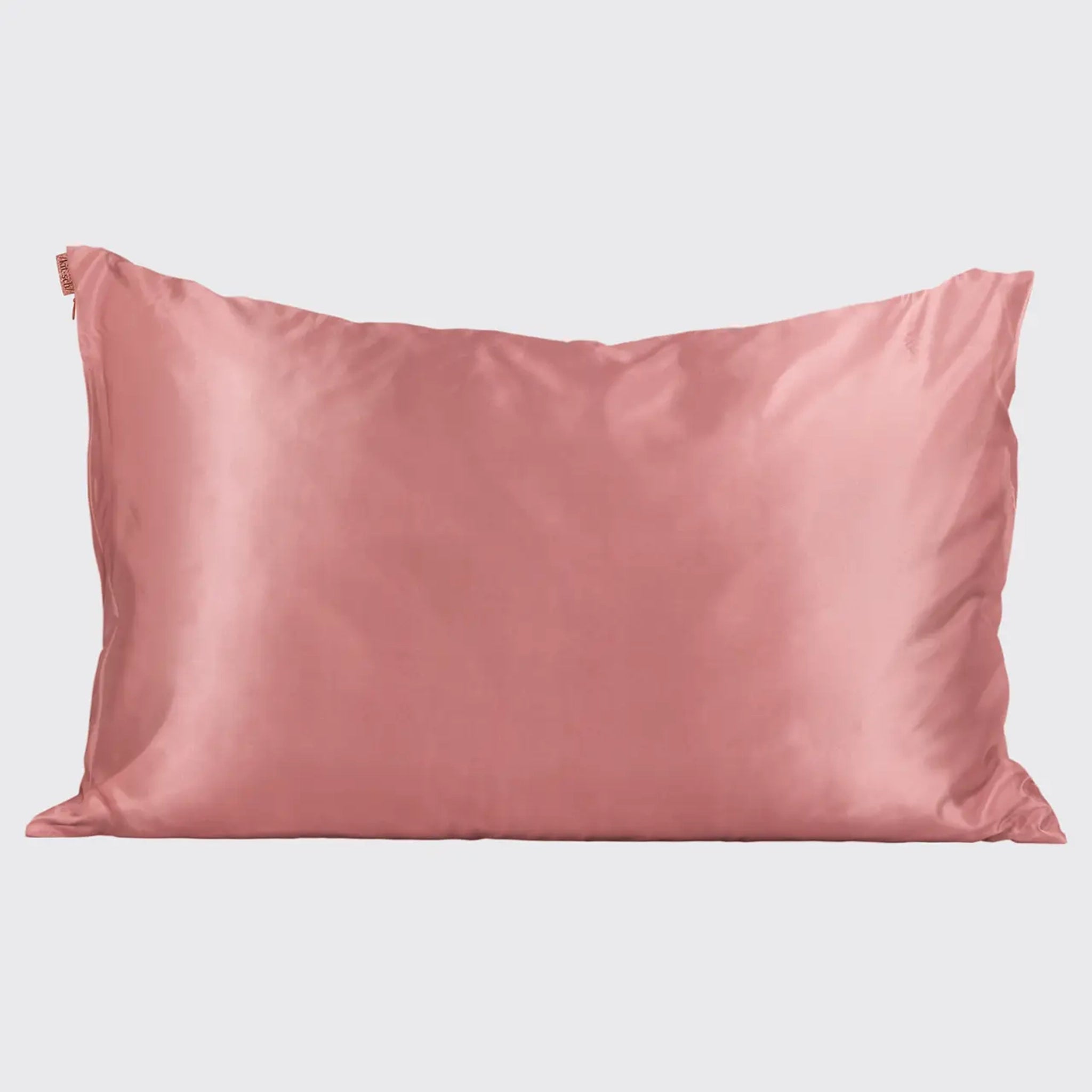 The rosey/terracotta colored satin pillow case on a pillow (not included).