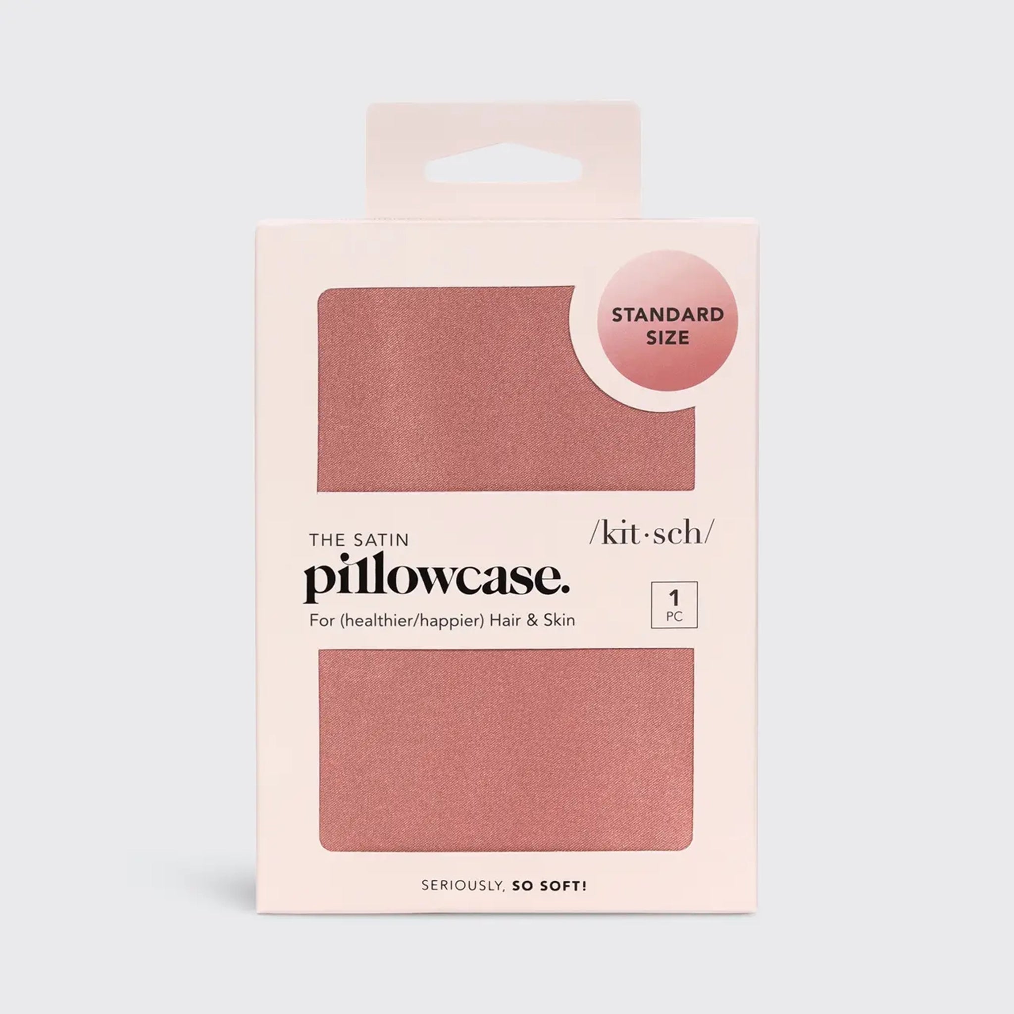 A rose pink/ terracotta satin pillow case folded up in its pink packaging  along with text that reads, "Standard Size" "The Satin Pillowcase For (healthier/happier) Hair & Skin" "1 PC".