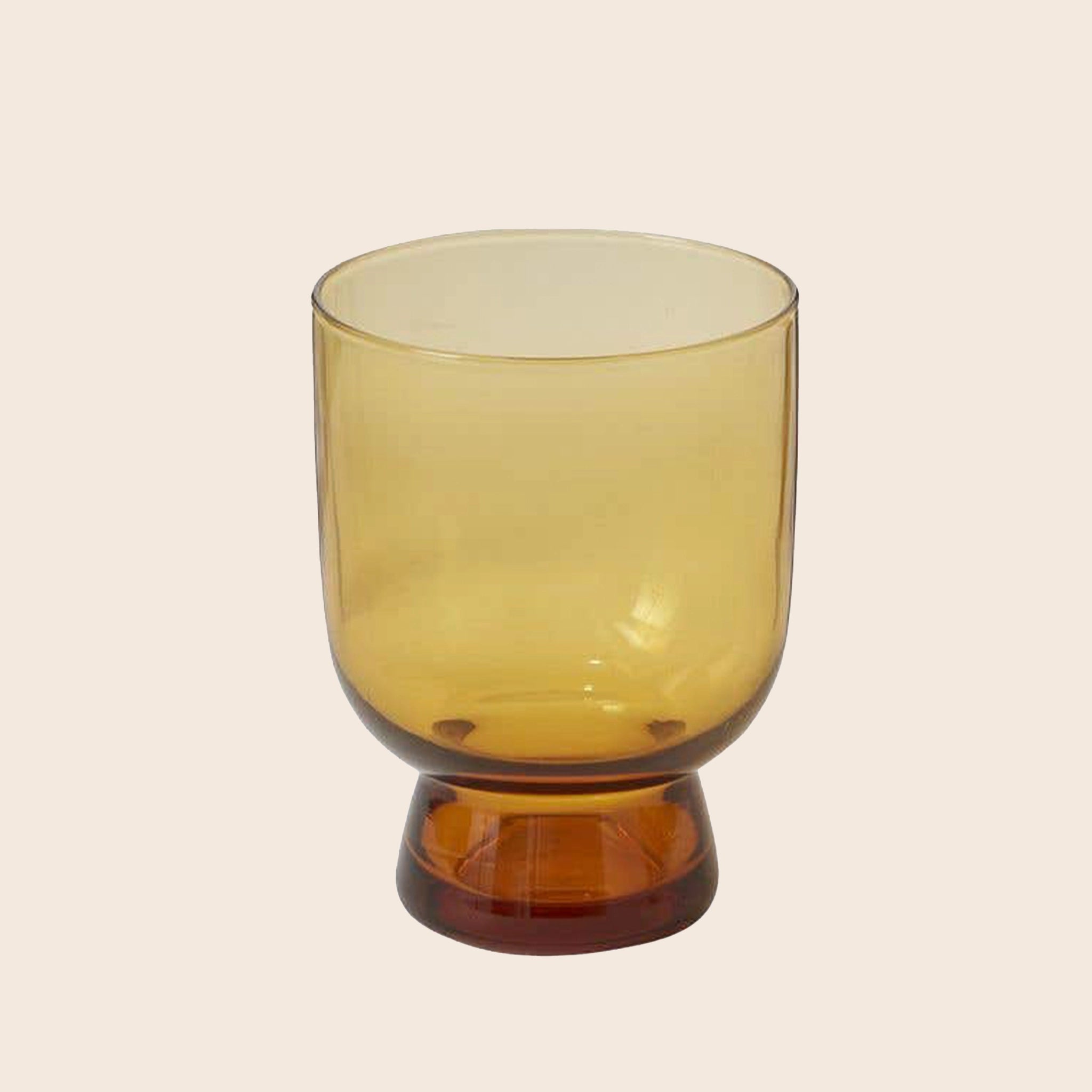 A glass cup with an amber hue and a pedestal at the bottom. 