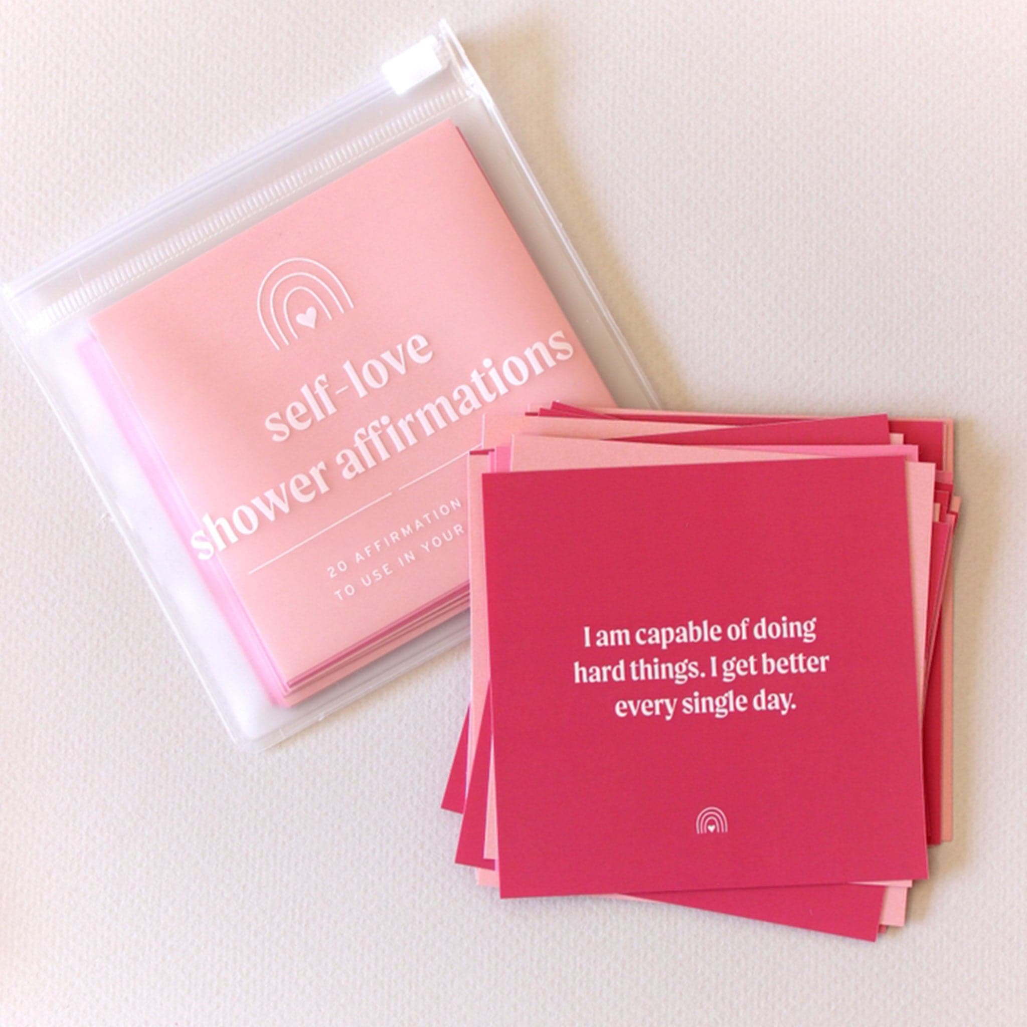 Different tones of pink cards that each have an uplifting affirmation on them for you to read and stick on the walls of your shower. 