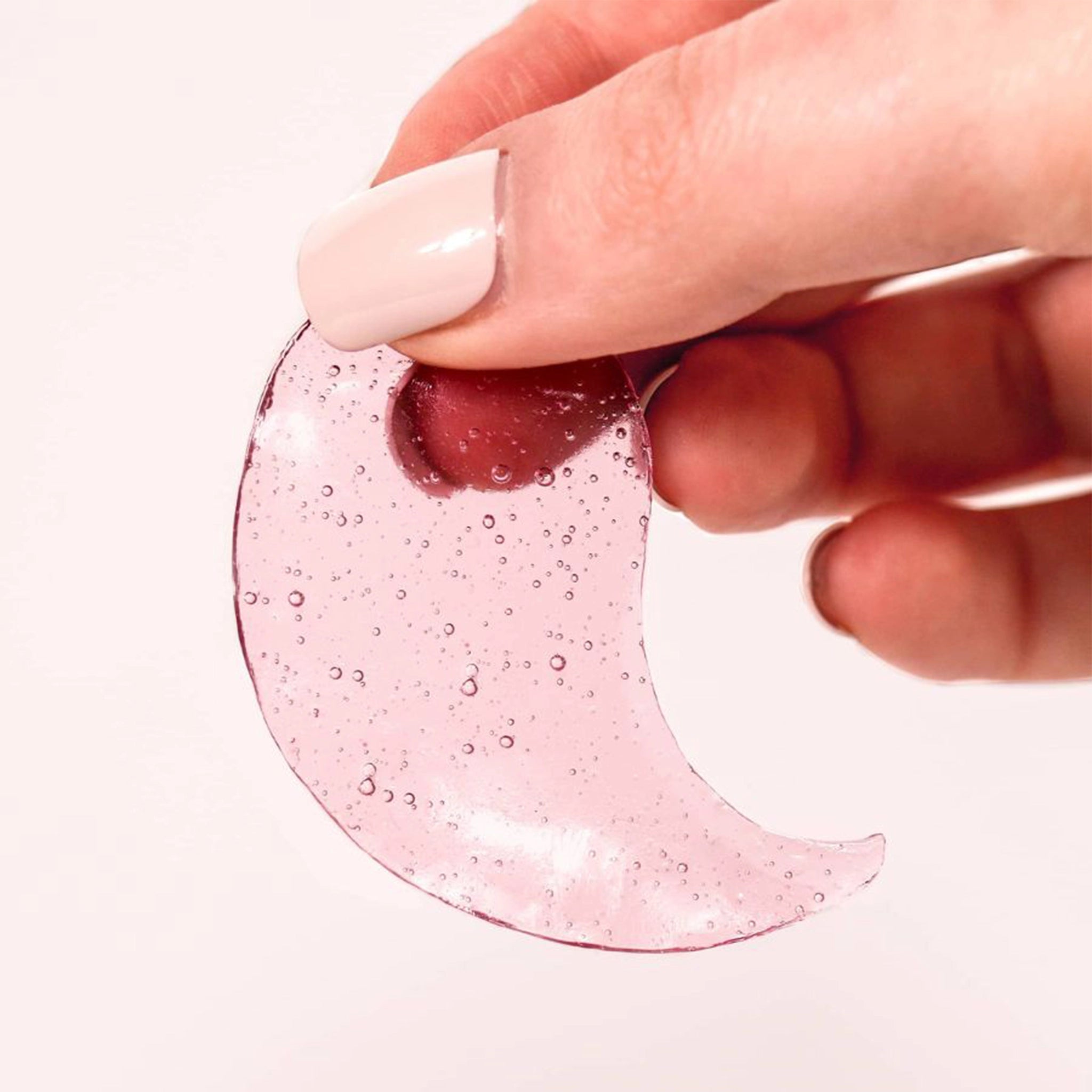 A model holding the eye gels out of the packaging. They are pink and jelly like.