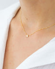 A super dainty gold chain necklace with a tiny bee pendant in the center.
