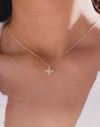 This is a picture of a woman’s neck. She is wearing a white shirt. Around her neck is a thin gold chain with a small gold bee charm in the middle.