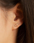 A cubic zirconia stud earring with 3 tiny baguette stones.