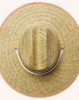 A wide brim sun set made of a neutral woven straw material with a white drawstring and tangerine orange detailing around the edge of the brim as well as the label in the center or the hat.
