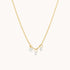 On a white background is a dainty gold chain necklace with three CZ stones hanging from the necklace. 