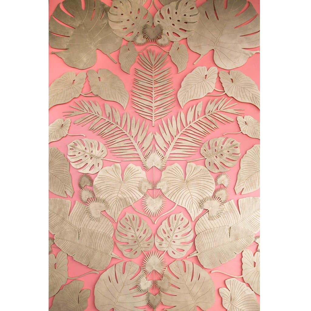 A flamingo colored wall with a mirrored pattern of a variety of natural wood cut tropical plant leaves.