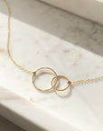 the unity necklace features two gold circles, hand forged and lightly hammered that come together and hang from a beautiful chain.