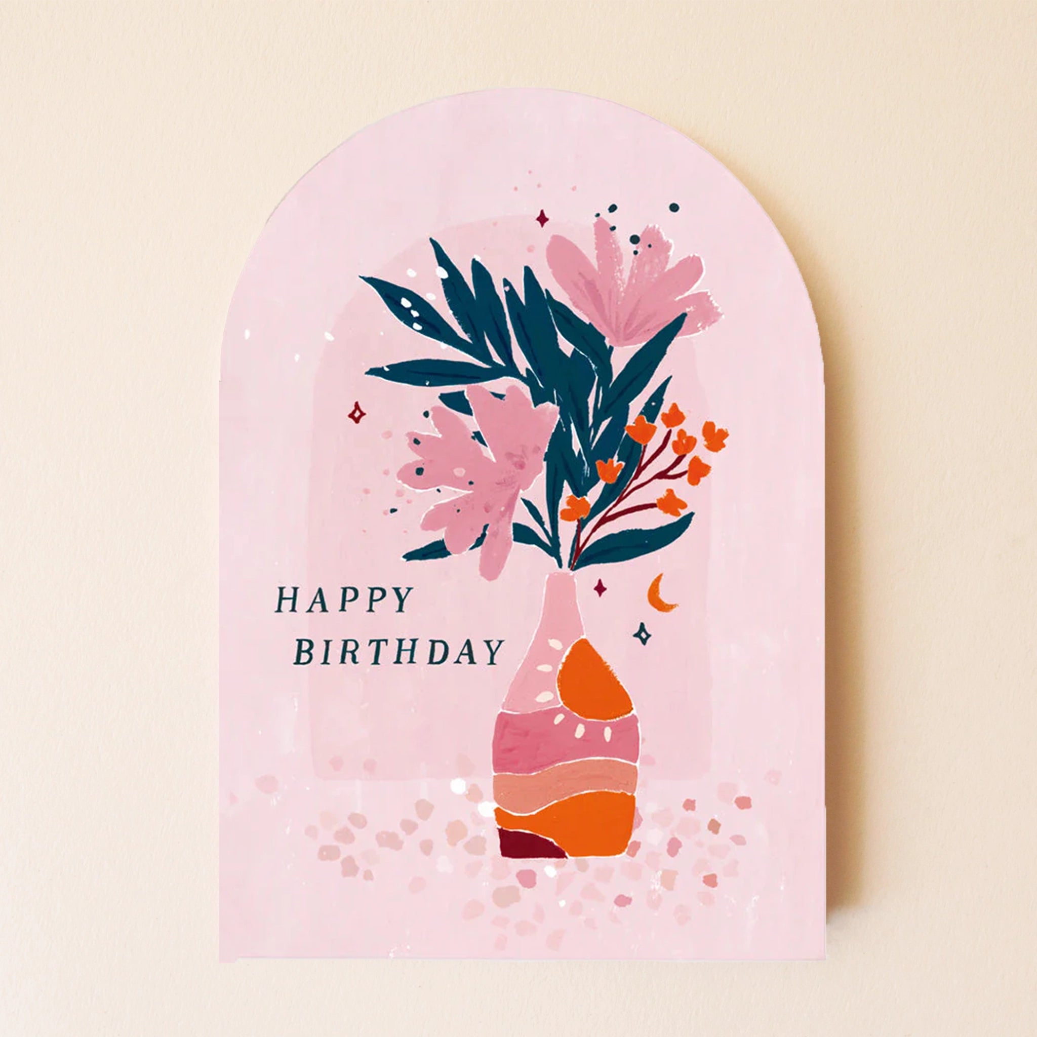 A pink arched birthday card with an illustration of a pink and orange striped vase with a green, pink and orange flower arrangement inside as well as text on the left that reads &quot;Happy Birthday&quot;.