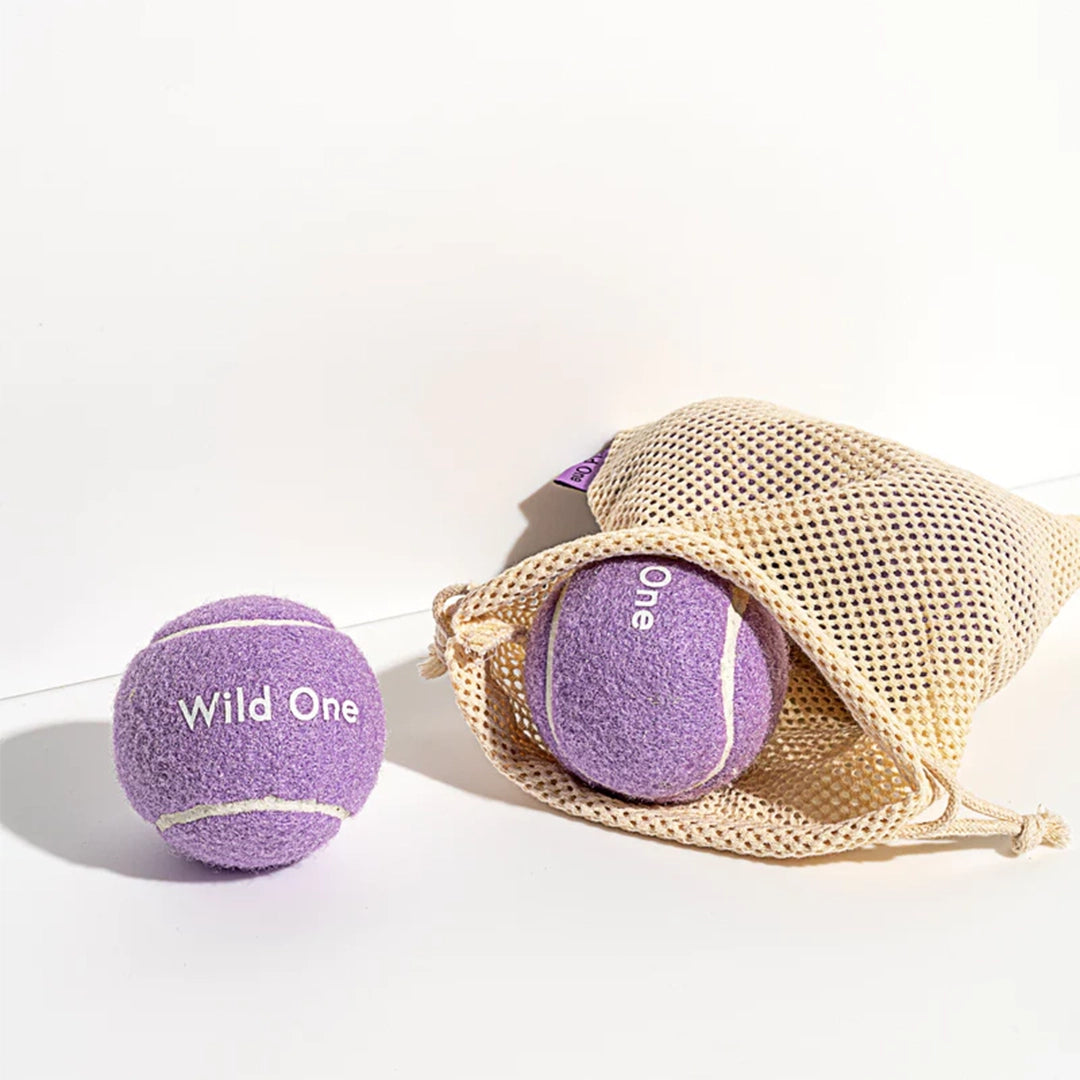 Purple tennis balls that read, &quot;Wild One&quot; in white text.