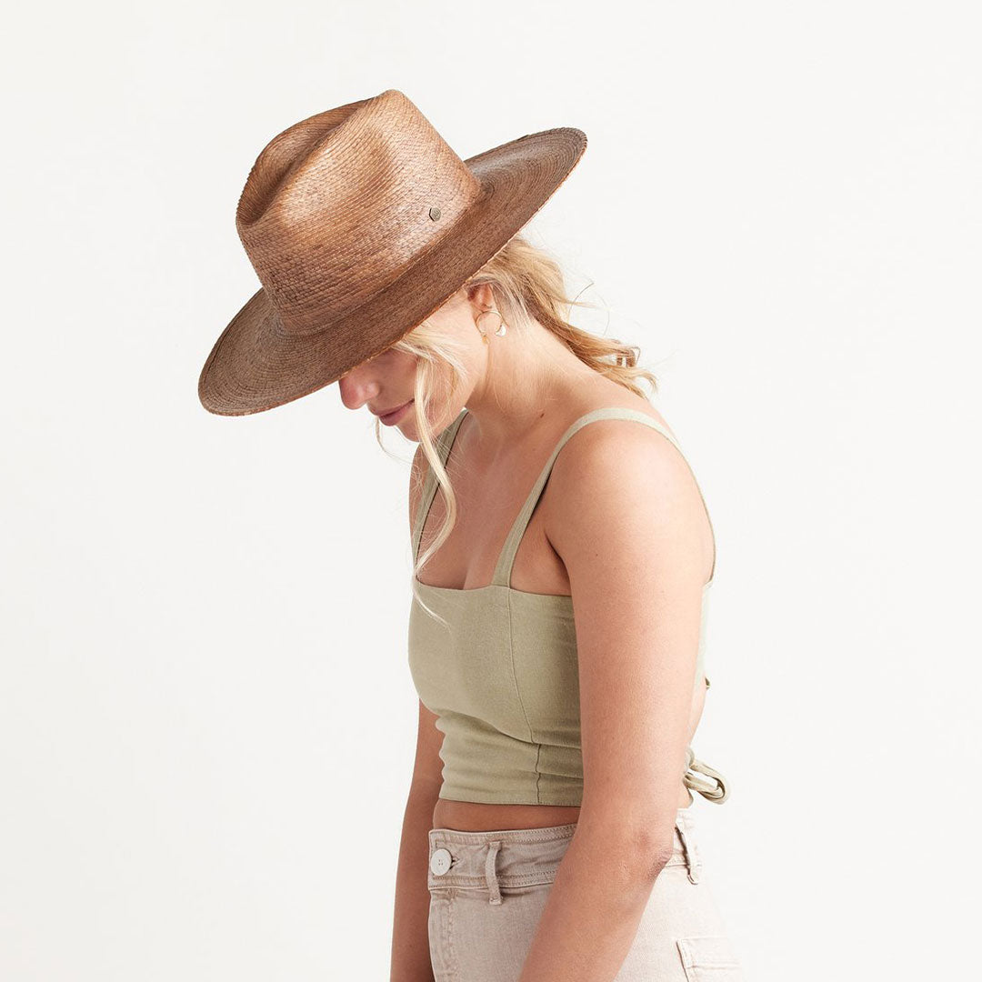 a woman with blonde hair modeling a light brown straw hat