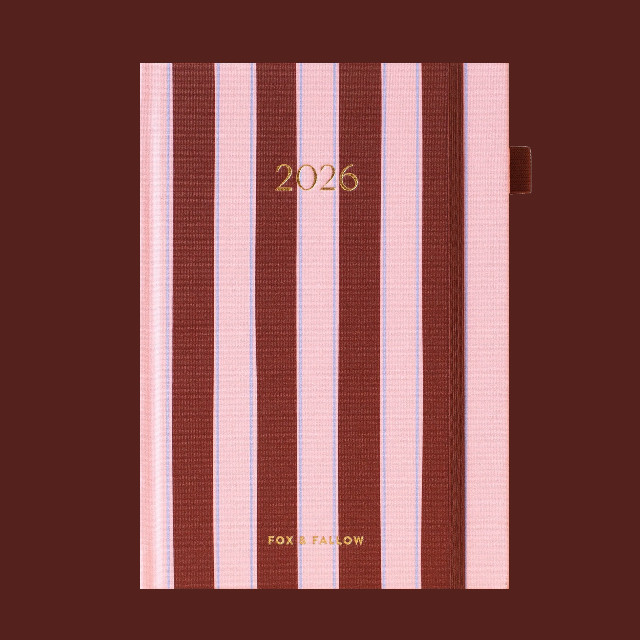 A burgundy and pink striped planner with gold foiled text that reads, '2026'. 
