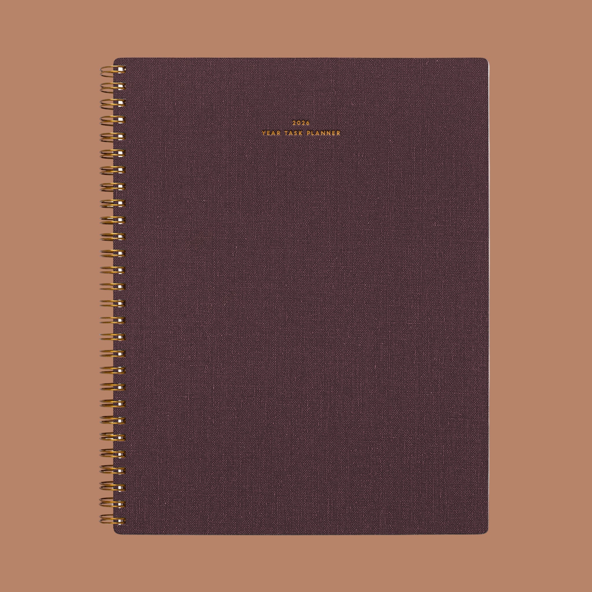 A burgundy planner with small gold foiled text that reads, "2026 Year Task Planner". 