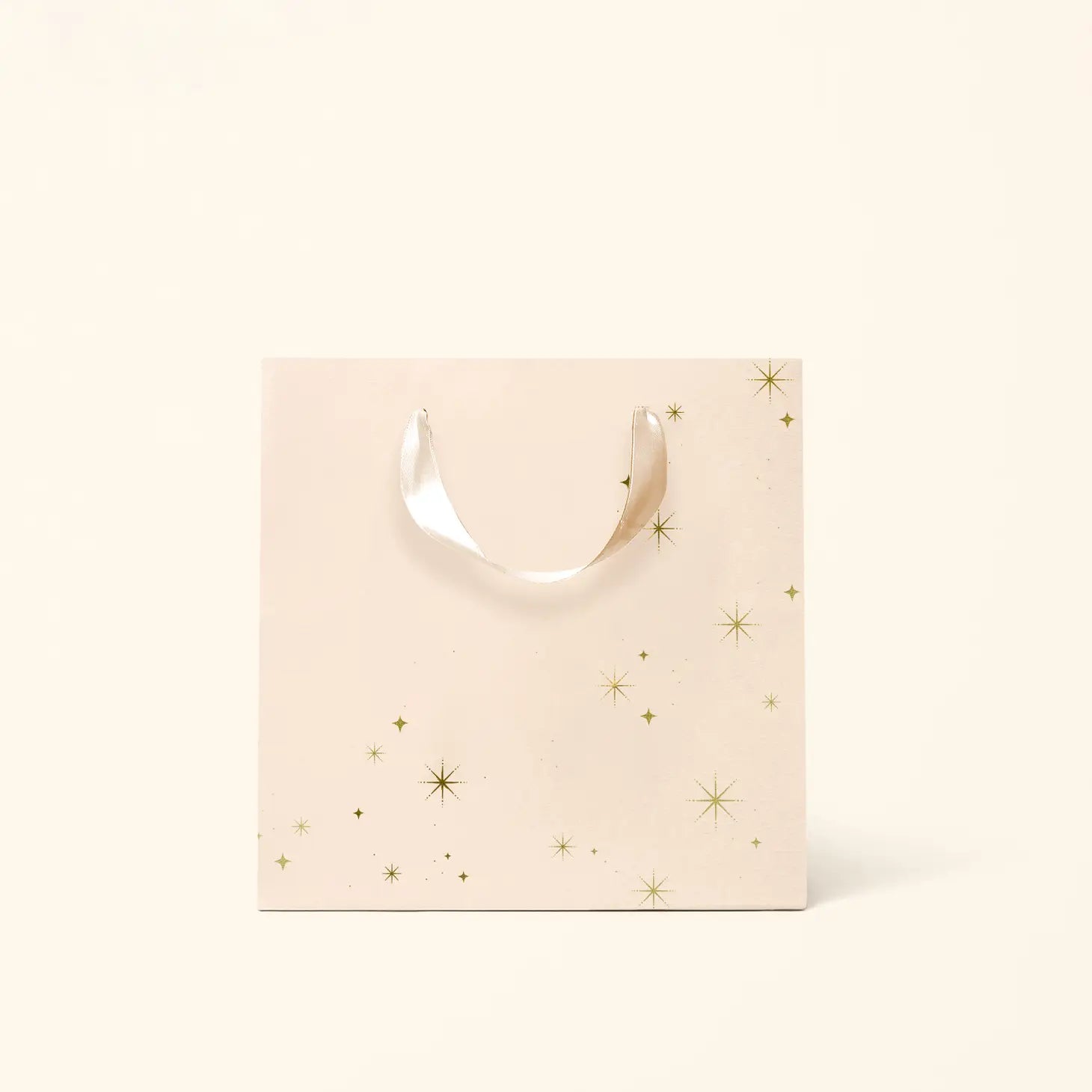On an ivory background is a light pink gift bag with gold star details.