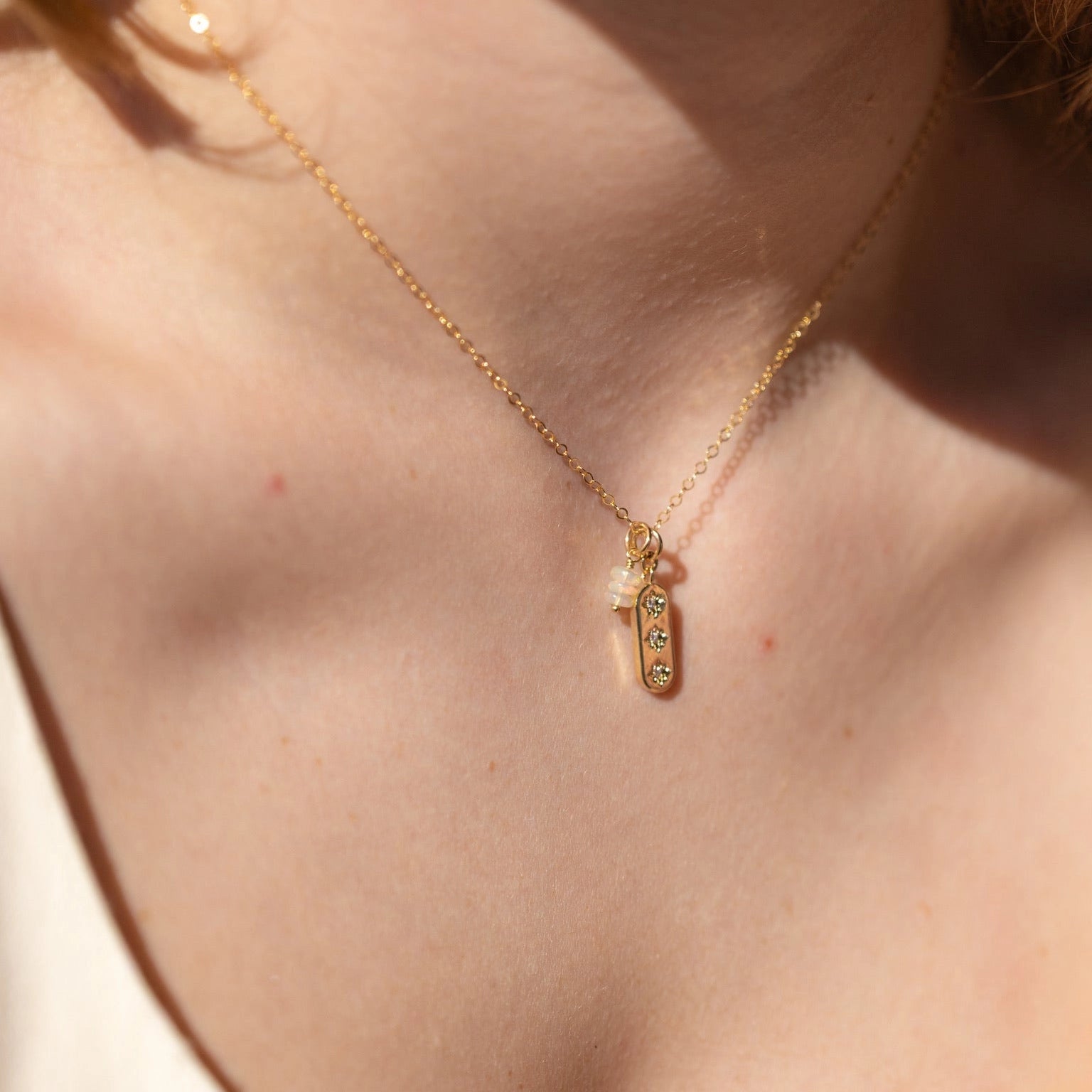 A model wearing a gold necklace with 3 stones on it.