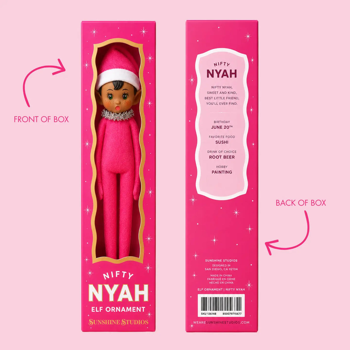 Front and back views of a pink retail box for a 'Nifty Nyah' elf ornament by Sunshine Studios, shown on a solid pink background with arrows labeling the front and back panels.
