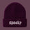 A dark purple ribbed knit beanie with the word 'spooky' embroidered in white Gothic lettering on the front cuff, set against a solid lavender background.