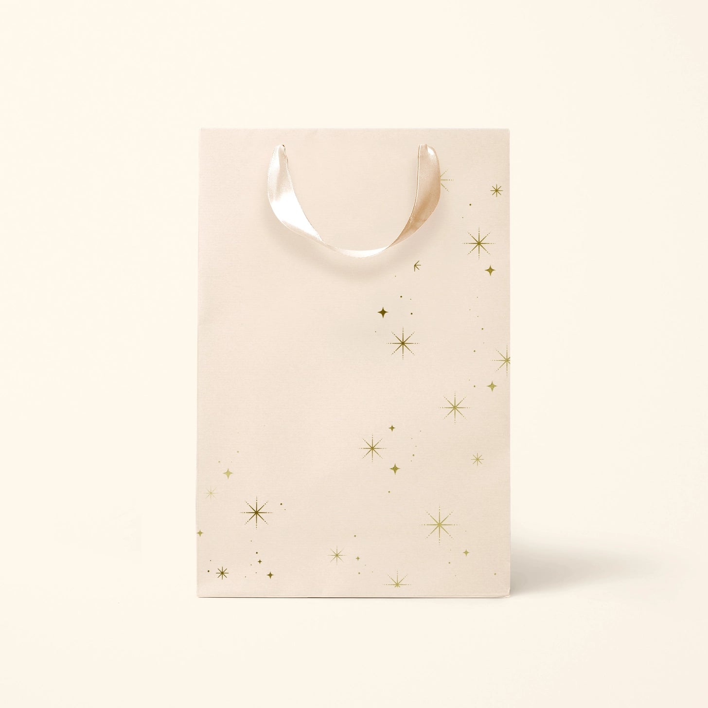 On an ivory background is a light pink gift bag with gold star details.