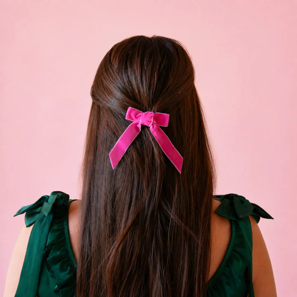 a pink velvet bow in a model's hair. 