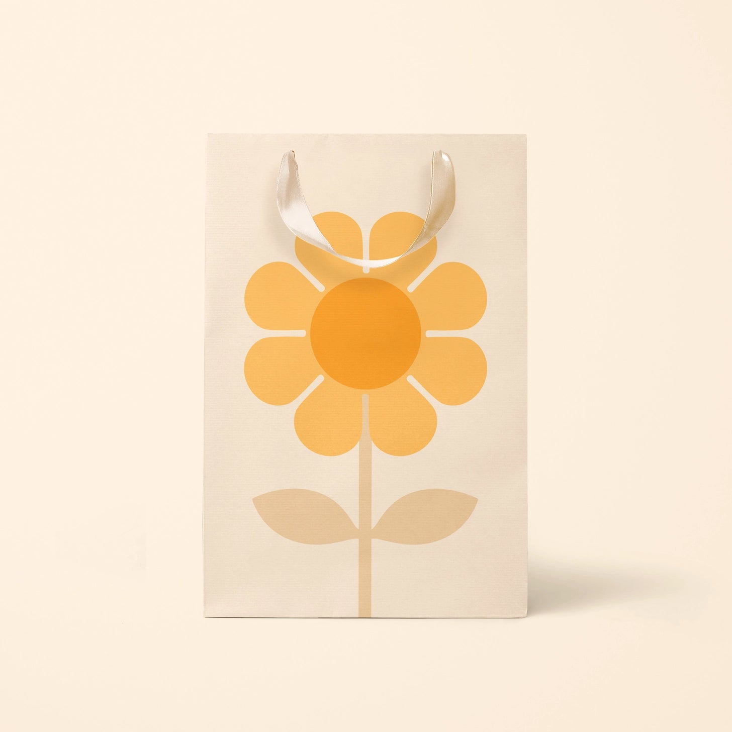 On a cream backgrounds the medium gift bag with a yellow and orange daisy in the center with ribbon handles. 