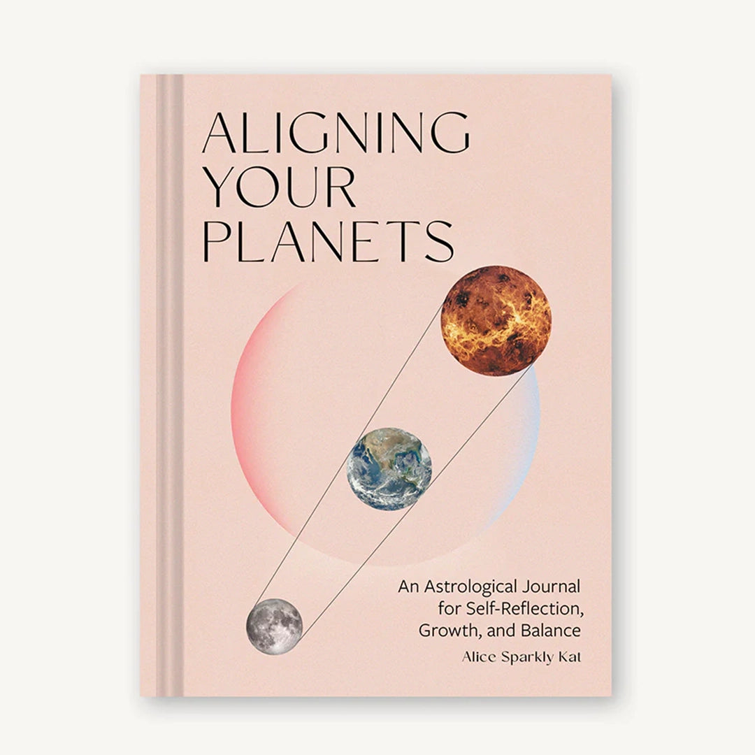 On a white background is a pink book cover with the title, "Aligning Your Planets", "An Astrological Journal for Self-Reflection, Growth and Balance" along with a graphic of three planets aligned. 