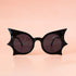 A black pair of sunglasses with a bat shape. 