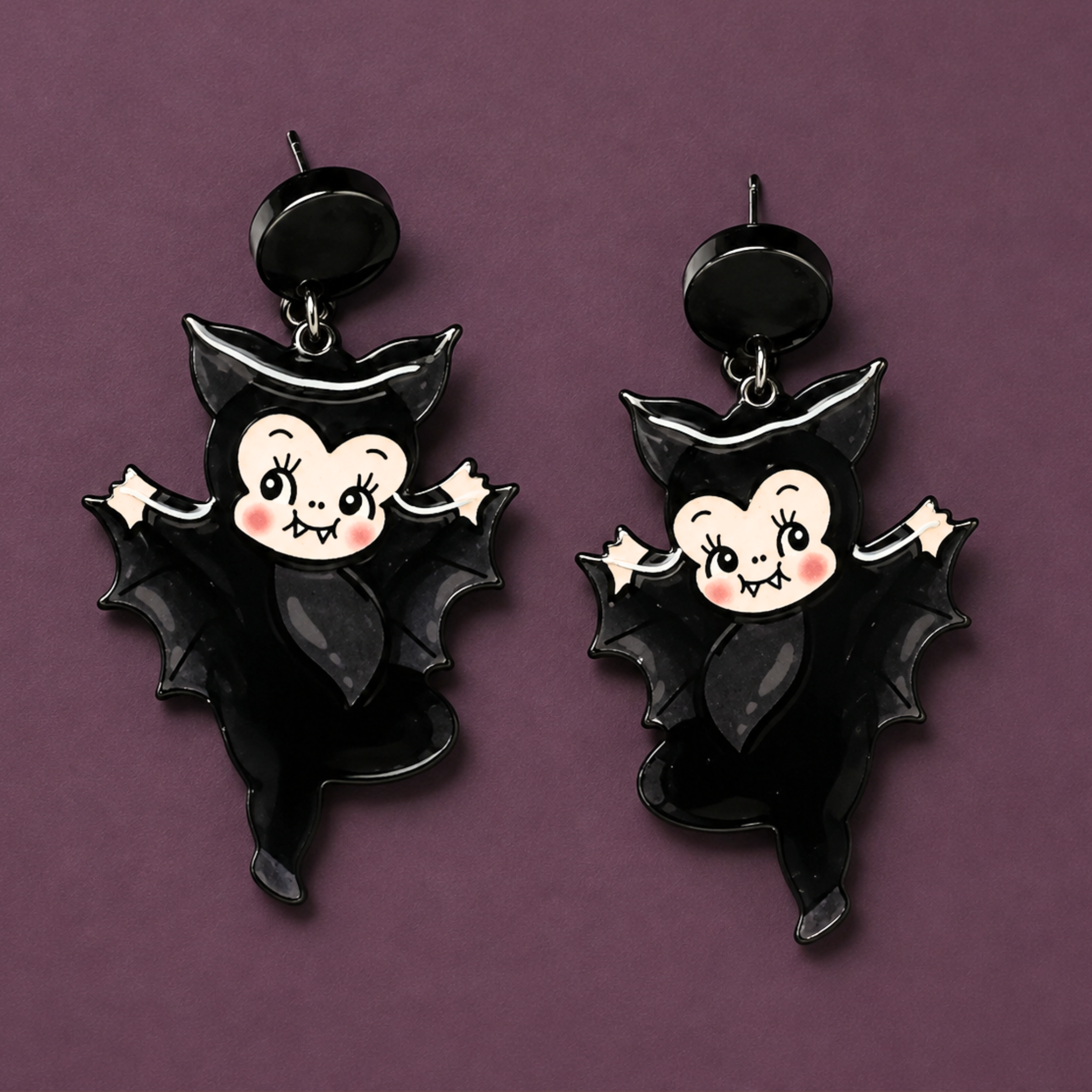 a pair of black bat kewpie doll shaped dangle earrings. 