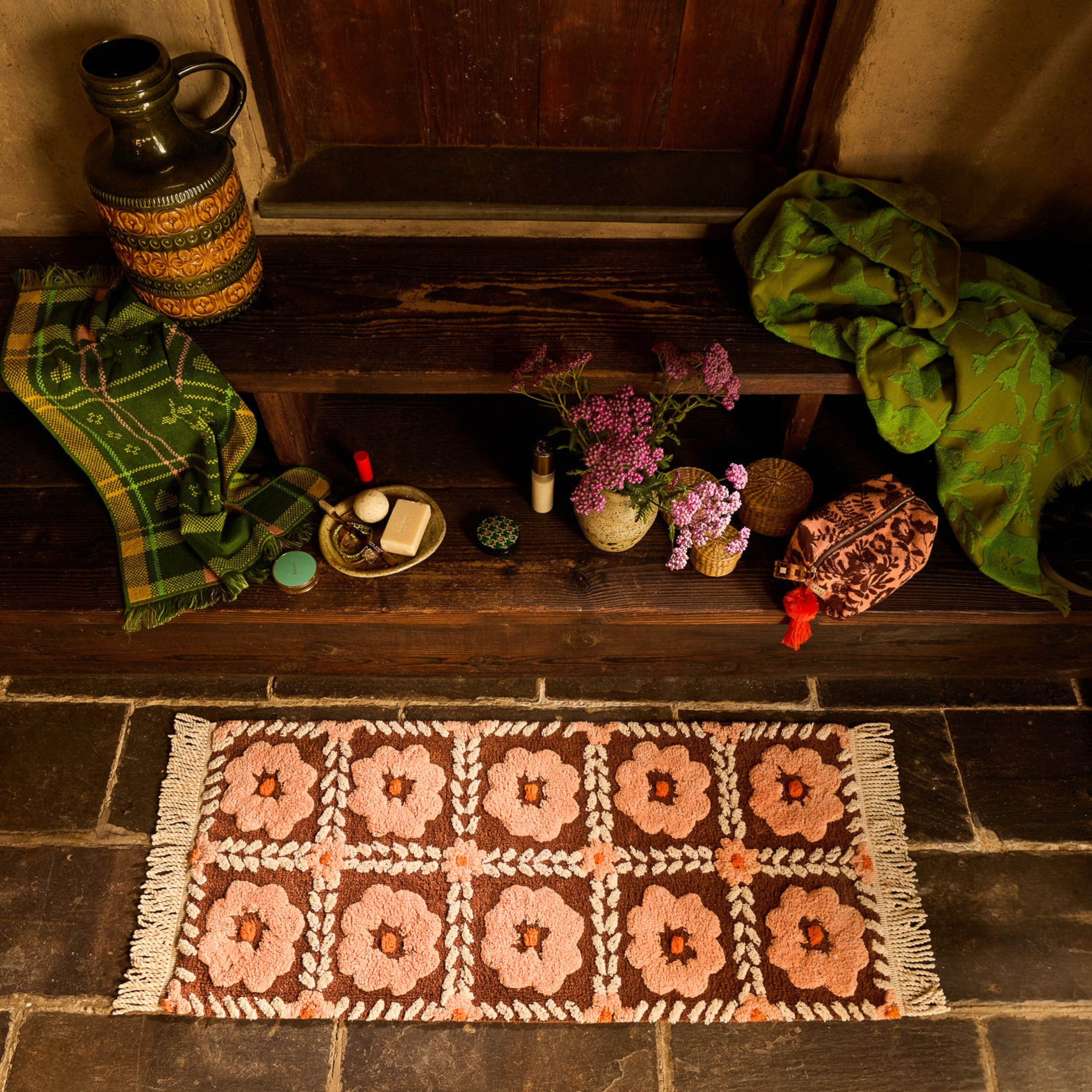 a floral bath mat with tassels on each end. 