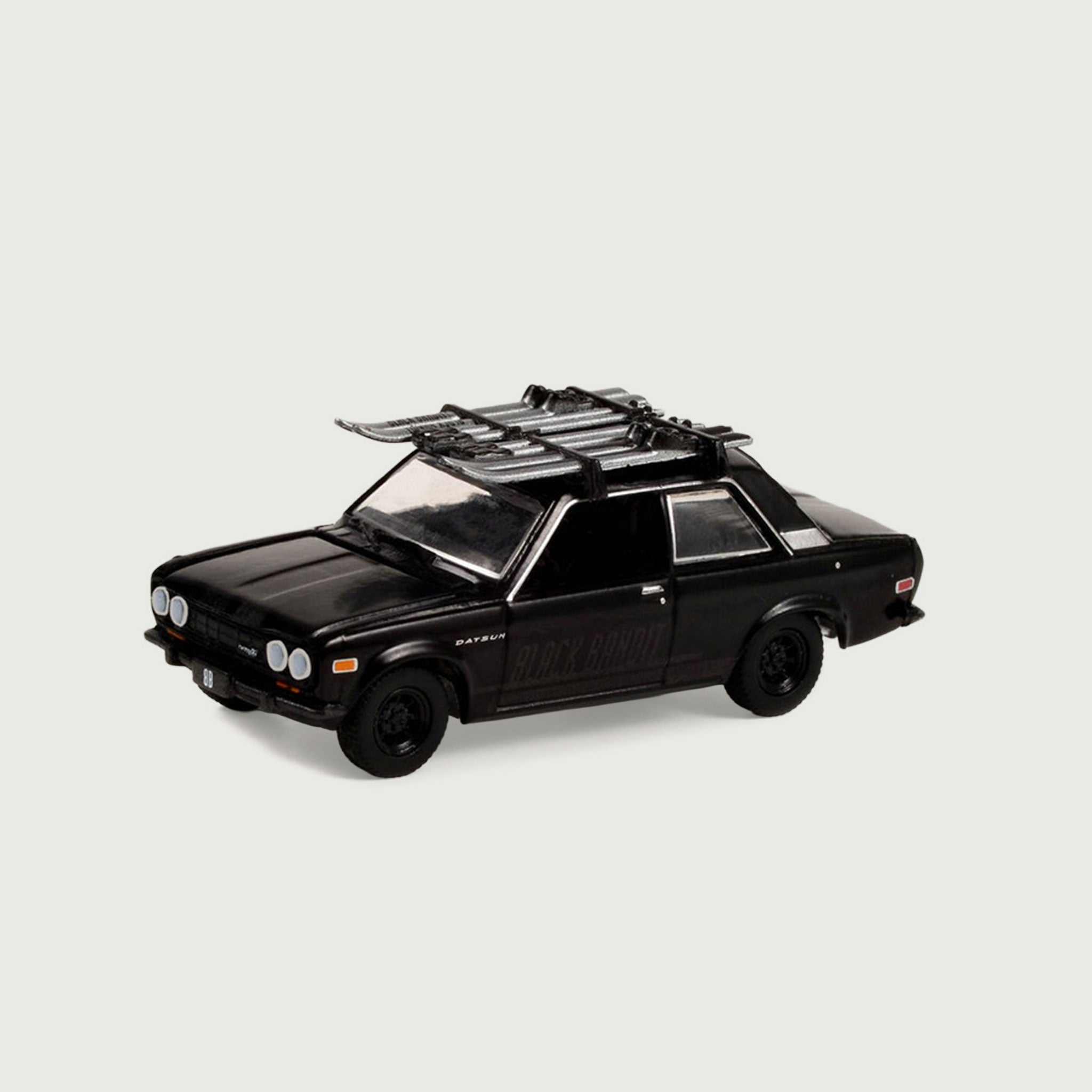 Black Datsun 510 toy car with roof rack holding skiis. 