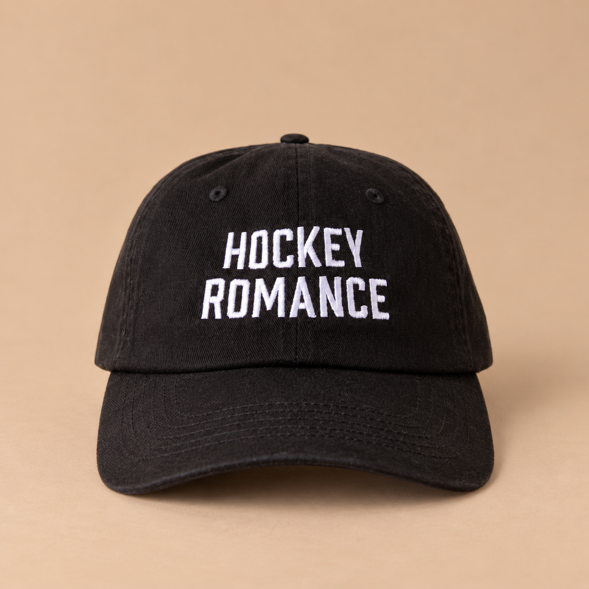 A black baseball cap with white embroidery that reads, "Hockey Romance". 