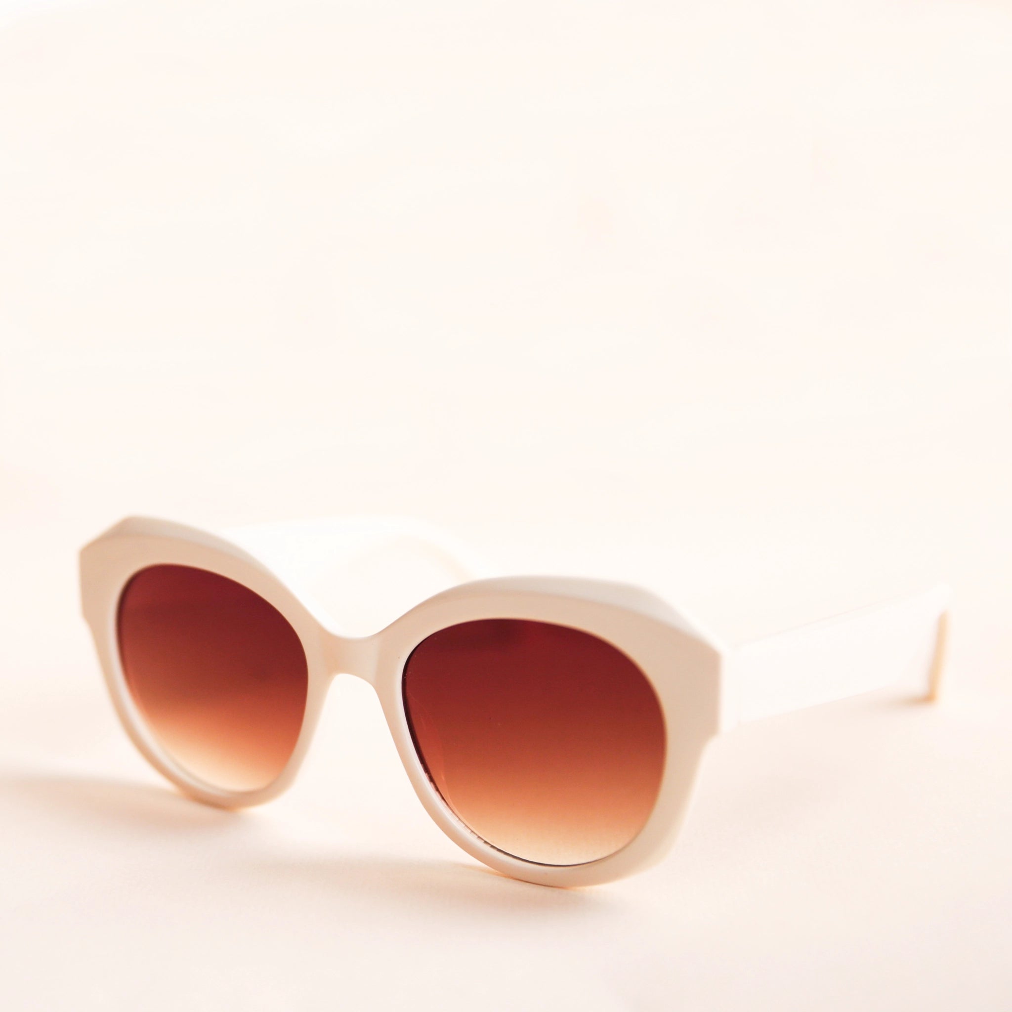White rounded chunky sunglasses with a brown lens.