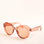 On a white background is a light brown translucent sunglasses that have a rounded shape and a light brown lens.