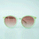 On a blue background is a light green pair of round sunglasses with a brown lens.